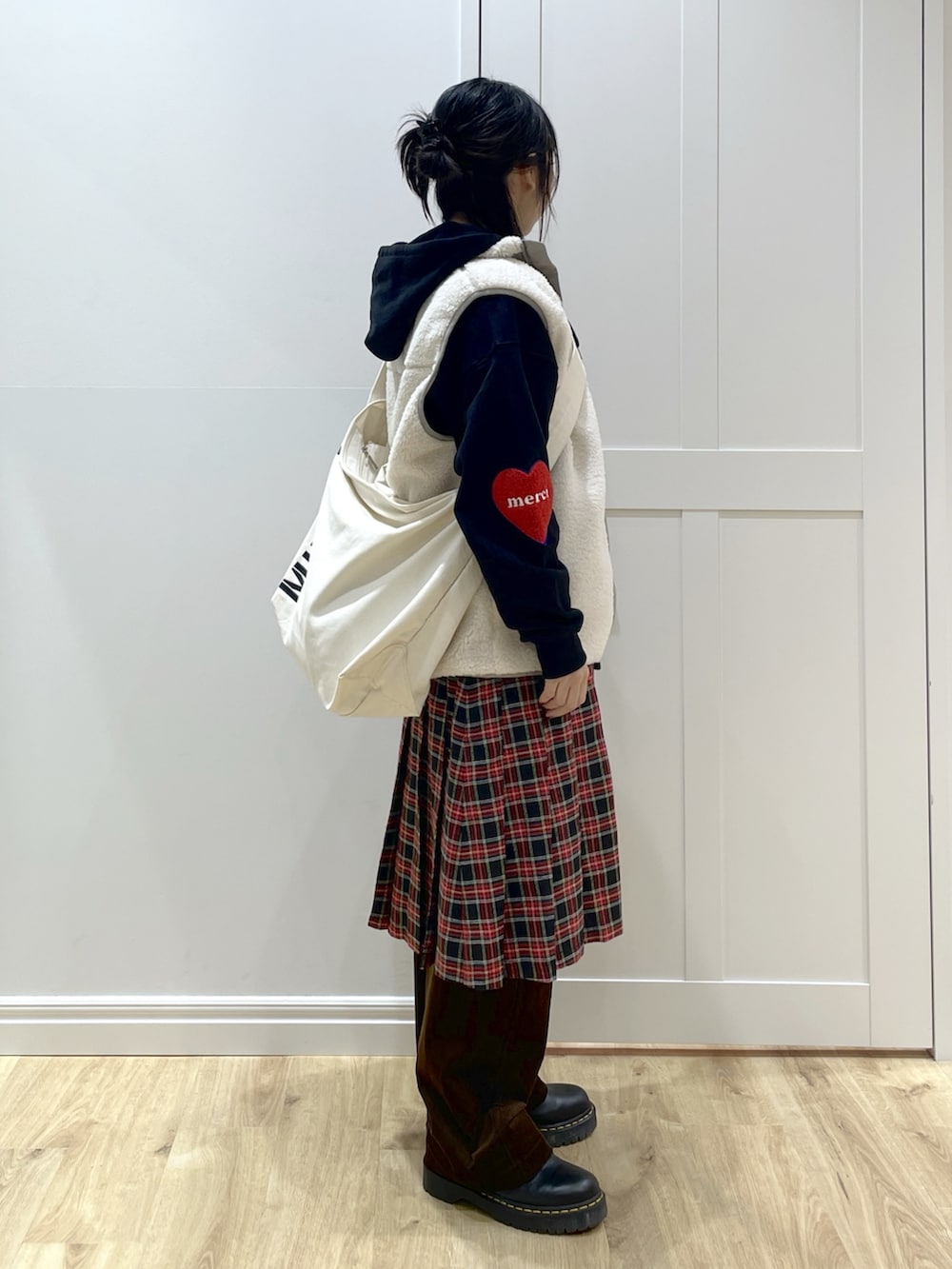 ホワイト系のベスト、ブラック系のパーカー、ブラック系のスカートを着用したレディースの秋コーディネートの4枚目の写真