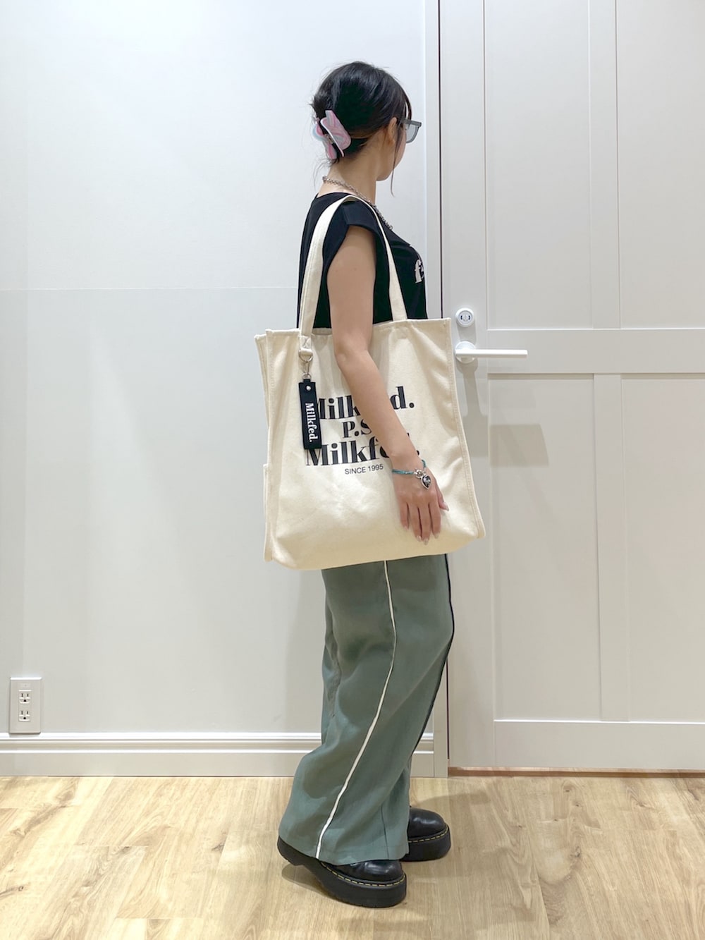 ホワイト系のトートバッグ、ブラック系のブーツ、グリーン系のその他パンツを着用したレディースの春コーディネートの2枚目の写真