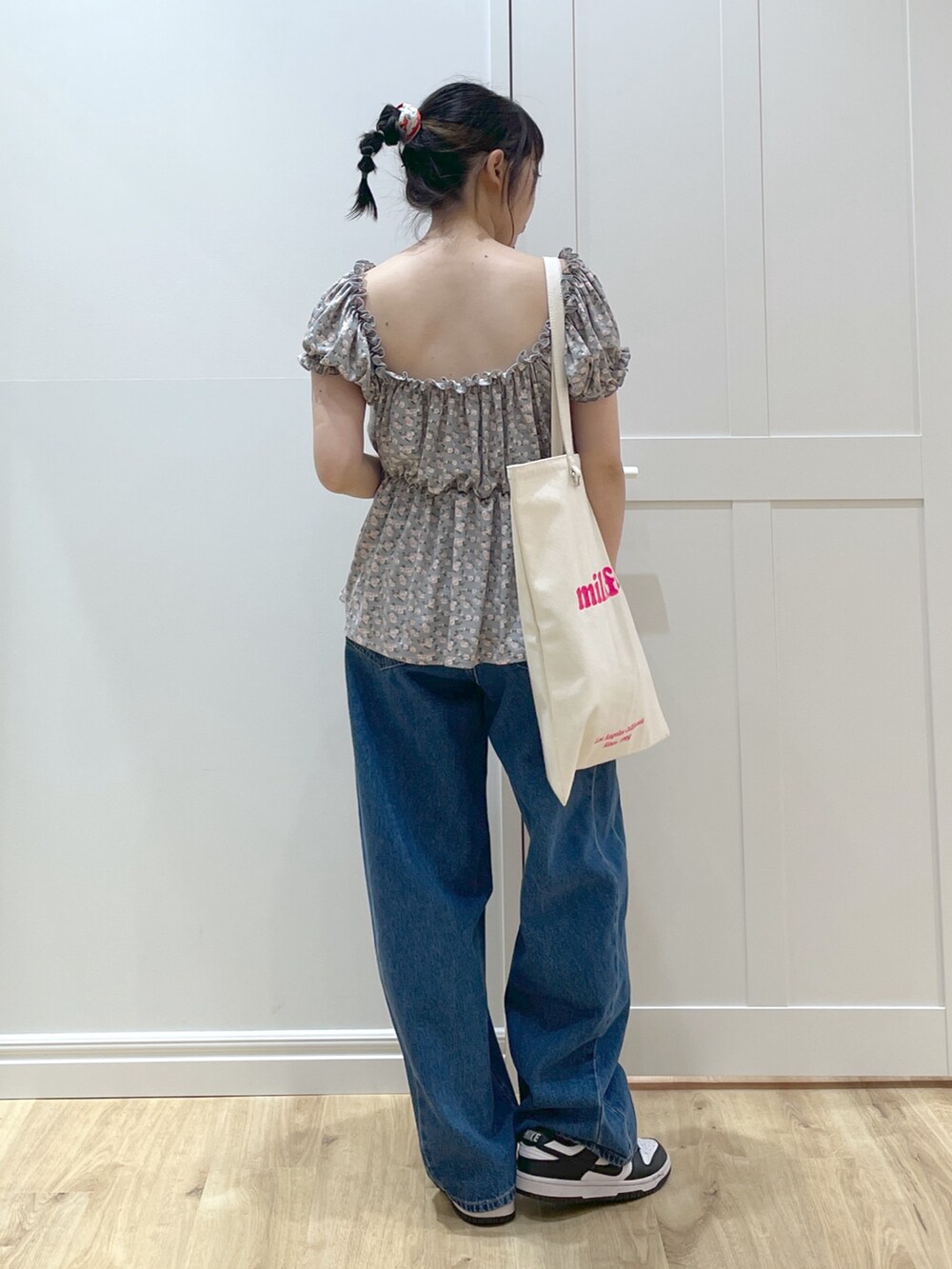 ブルー系のデニムパンツ、ホワイト系のスニーカー、ホワイト系のトートバッグを着用したレディースの春コーディネートの2枚目の写真