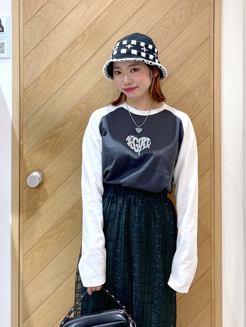 ブラック系のショルダーバッグ、グリーン系のスカート、ブラック系のブーツを着用したレディースの秋コーディネートの2枚目の写真