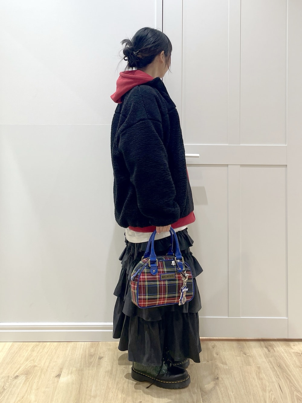 ブラック系のブーツ、ブラック系のショルダーバッグ、ブラック系のスカートを着用したレディースの冬コーディネートの3枚目の写真