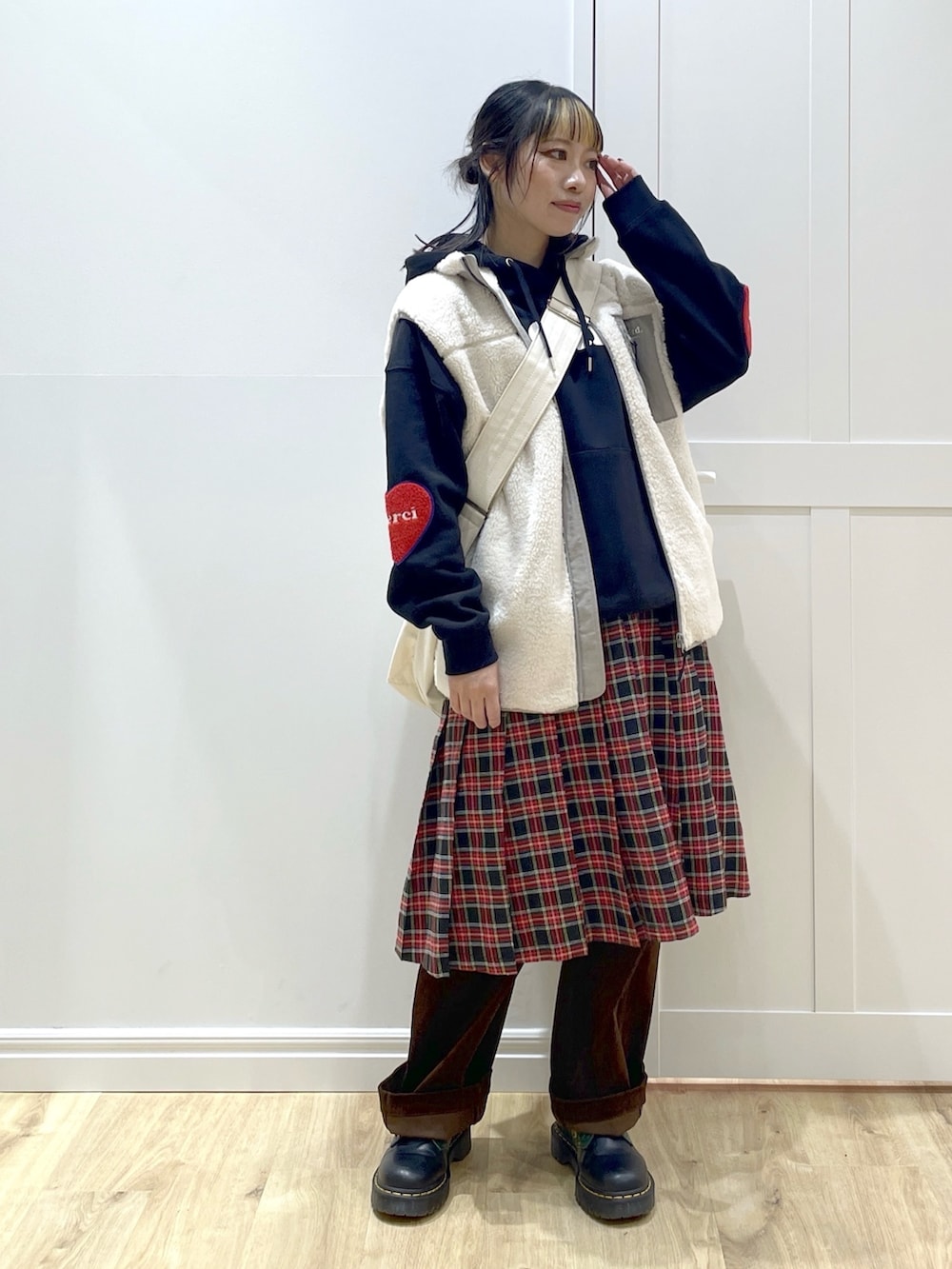 ホワイト系のベスト、ブラック系のパーカー、ブラック系のスカートを着用したレディースの秋コーディネートの3枚目の写真