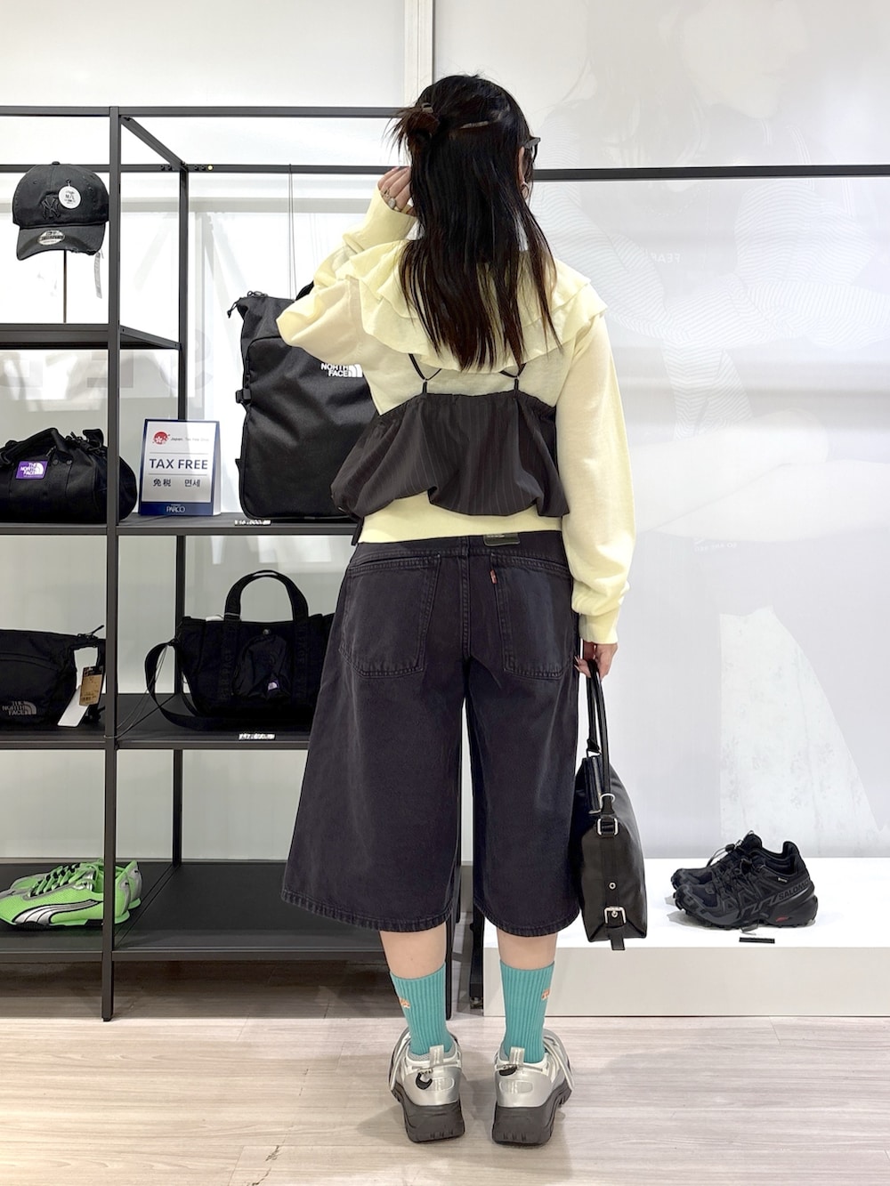 シルバー系のスニーカー、ブラック系のハンドバッグ、ブラック系のデニムパンツを着用したレディースの春コーディネートの4枚目の写真