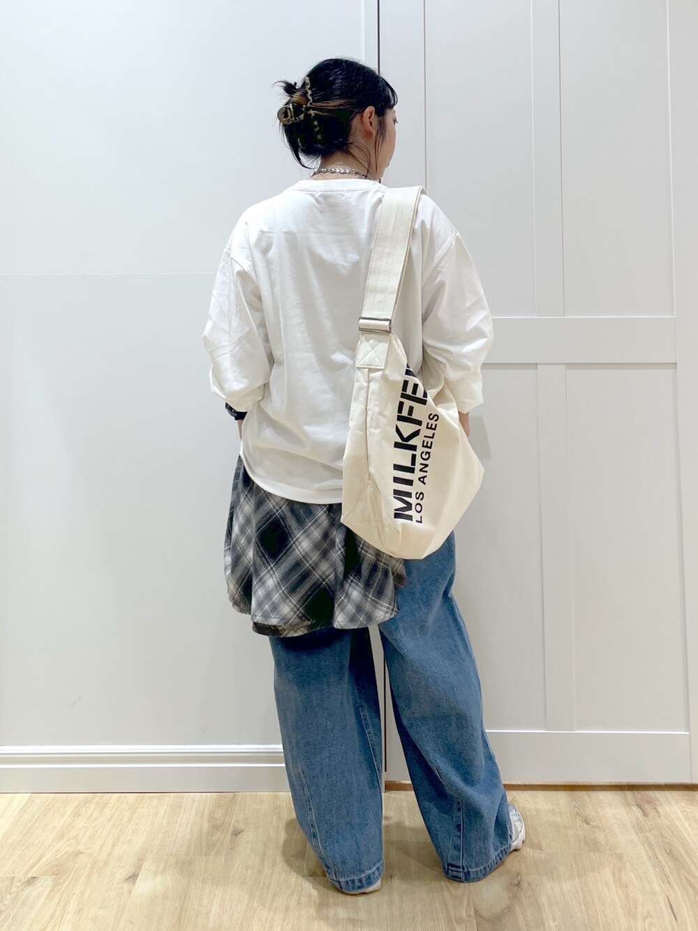 ホワイト系のTシャツ/カットソー、ブラック系のシャツ/ブラウス、ブルー系のデニムパンツを着用したレディースの秋コーディネートの2枚目の写真