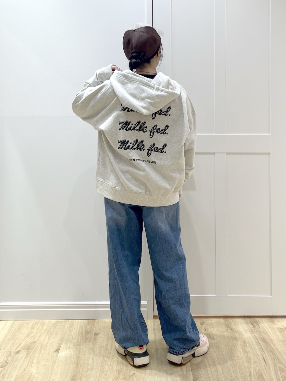 ベージュ系のパーカー、ブルー系のデニムパンツ、ブラック系のカーディガン/ボレロを着用したレディースの冬コーディネートの2枚目の写真