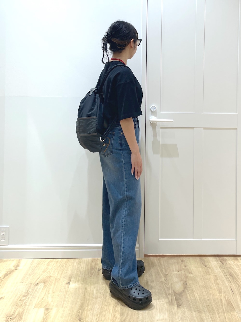 ブルー系のデニムパンツ、ブラック系のTシャツ/カットソー、ブラック系のサンダルを着用したレディースの春コーディネートの2枚目の写真