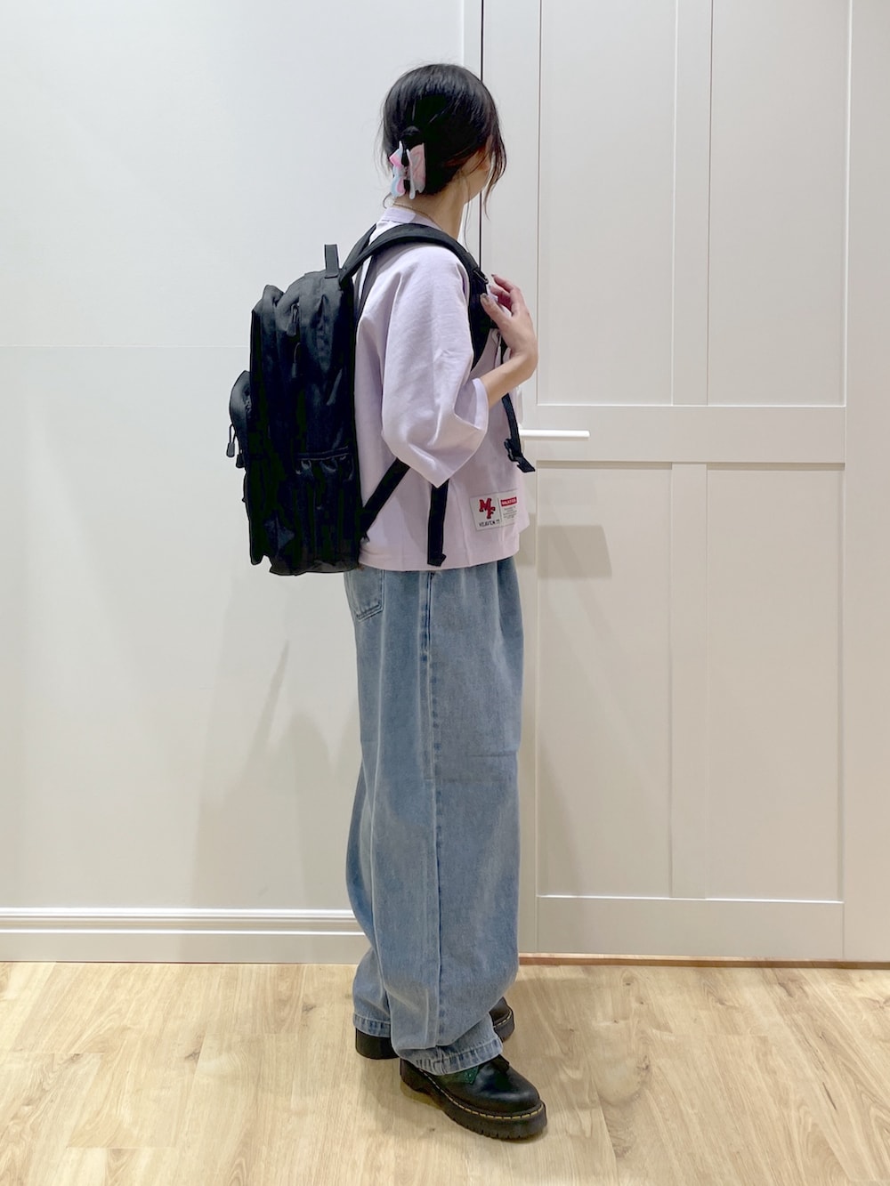 ブルー系のデニムパンツ、パープル系のTシャツ/カットソー、ブラック系のバックパック/リュックを着用したレディースの春コーディネートの2枚目の写真