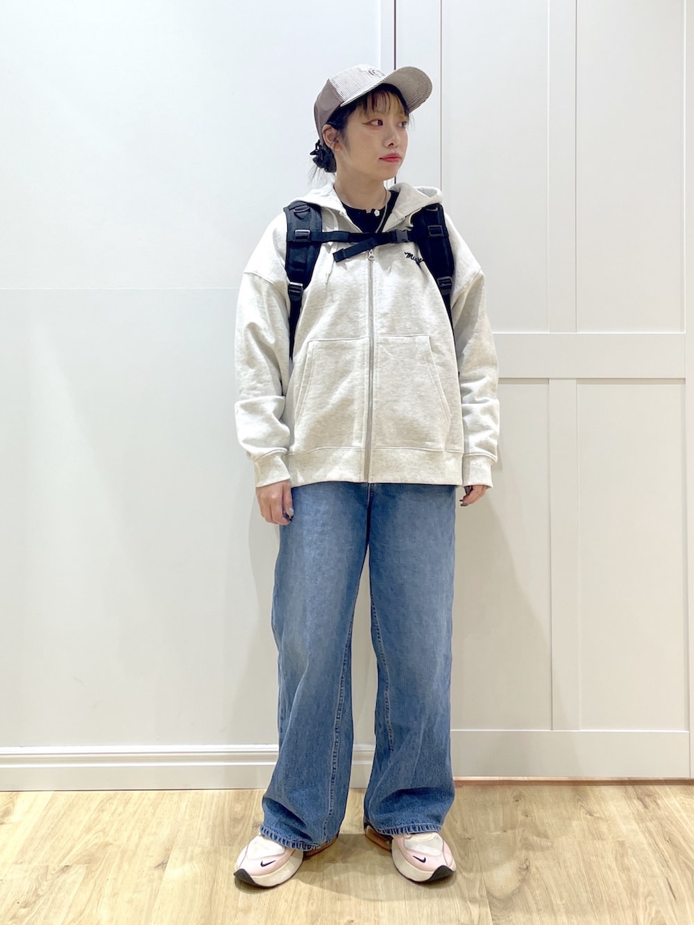 ベージュ系のパーカー、ブルー系のデニムパンツ、ブラック系のカーディガン/ボレロを着用したレディースの冬コーディネートの3枚目の写真