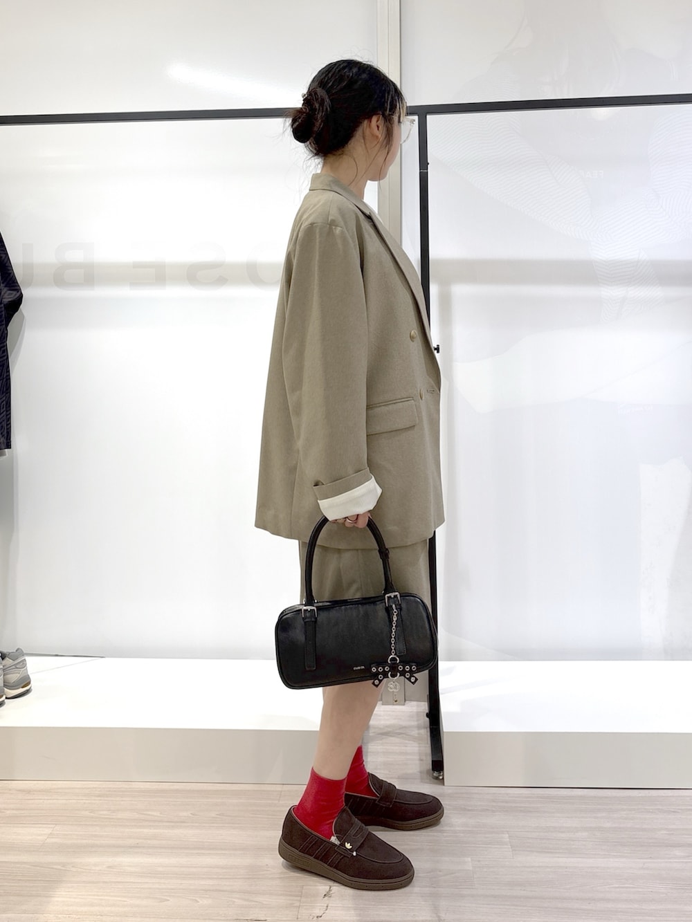 ホワイト系のシャツ/ブラウス、ブラック系のニット/セーター、ベージュ系のテーラードジャケットを着用したレディースの春コーディネートの2枚目の写真