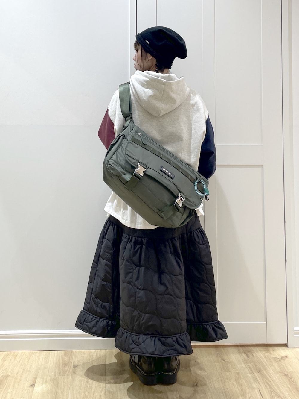 ブラック系のブーツ、グリーン系のメッセンジャーバッグ、ブラック系のスカートを着用したレディースの冬コーディネートの3枚目の写真