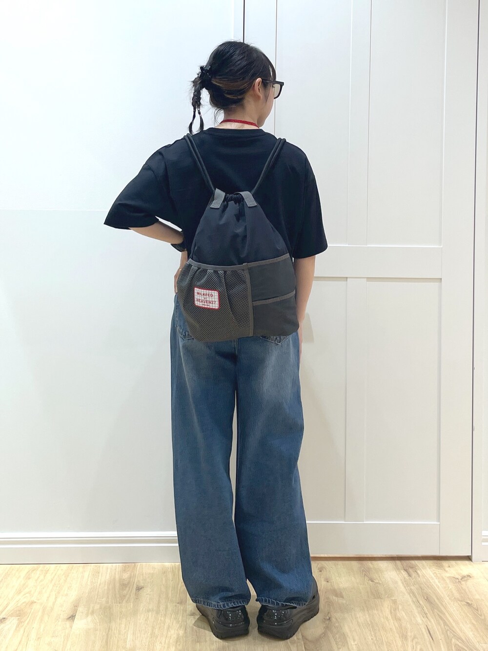 ブルー系のデニムパンツ、ブラック系のTシャツ/カットソー、ブラック系のサンダルを着用したレディースの春コーディネートの3枚目の写真