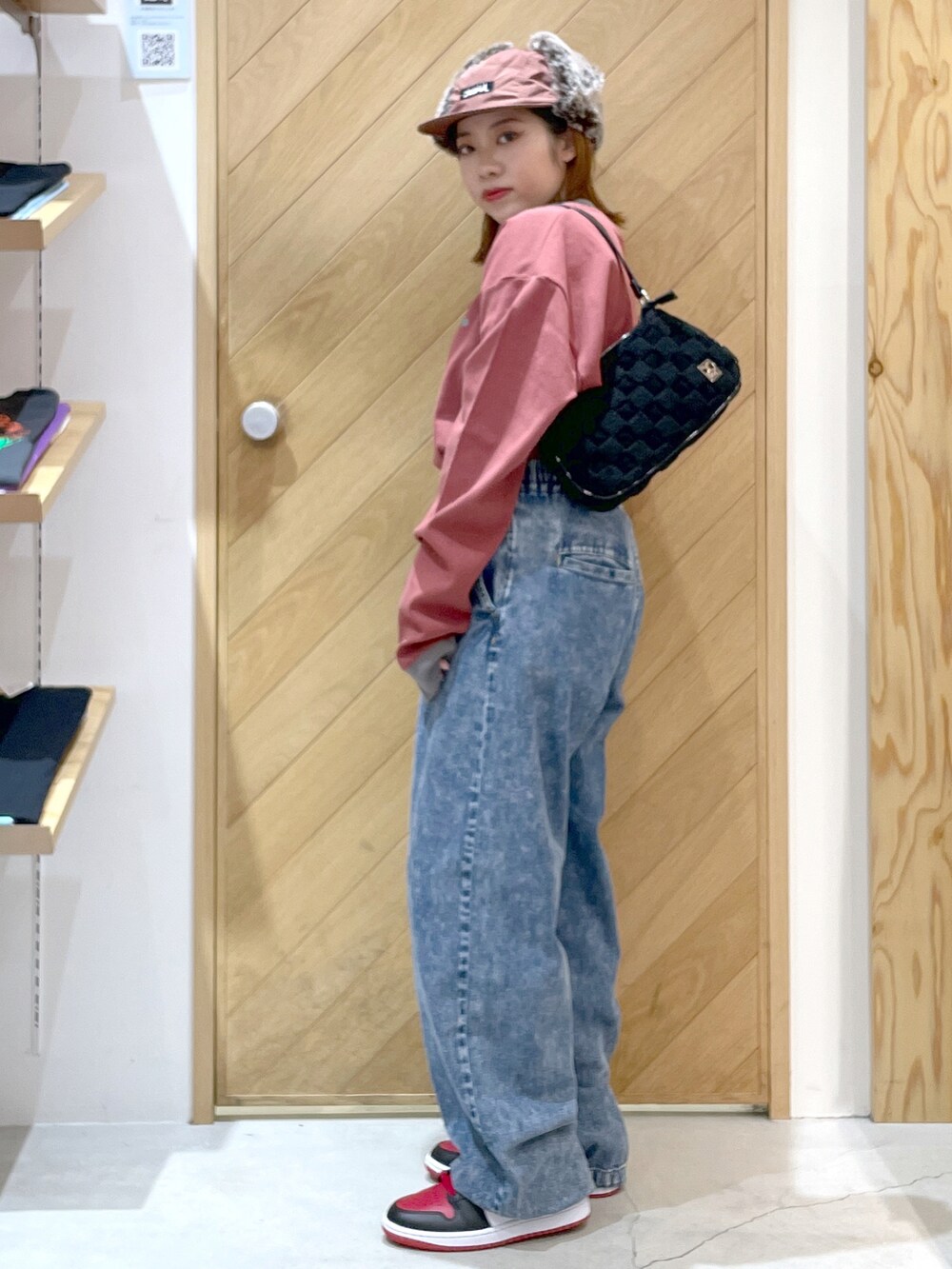 ブルー系のデニムパンツ、レッド系のスニーカー、ブラック系のハンドバッグを着用したレディースの秋コーディネートの2枚目の写真