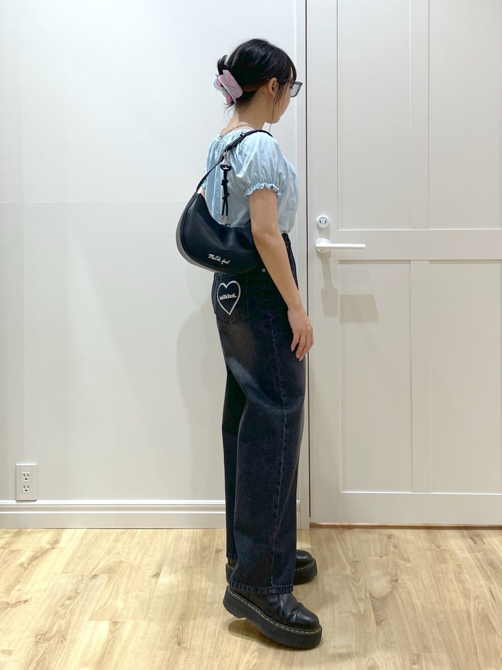 ブラック系のデニムパンツ、ブラック系のブーツ、ブラック系のハンドバッグを着用したレディースの春コーディネートの3枚目の写真