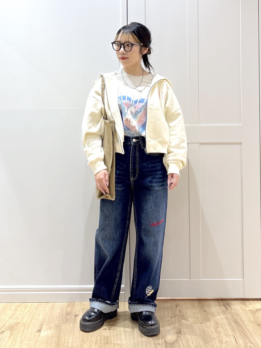 ブラック系のブーツ、ブルー系のデニムパンツ、ホワイト系のパーカーを着用したレディースの春コーディネートの4枚目の写真