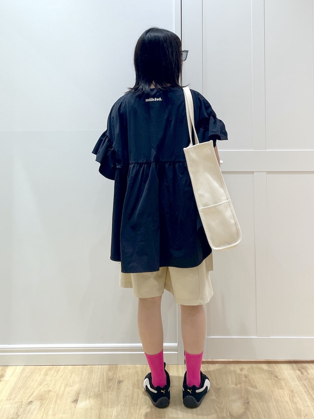 ブラック系のスニーカー、ホワイト系のトートバッグ、ブルー系のサングラスを着用したレディースの夏コーディネートの3枚目の写真