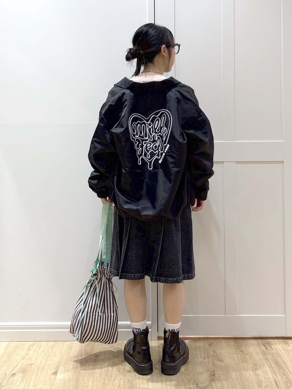 ブラック系のブルゾン、ピンク系のTシャツ/カットソー、ブラック系のデニムスカートを着用したレディースの春コーディネートの2枚目の写真