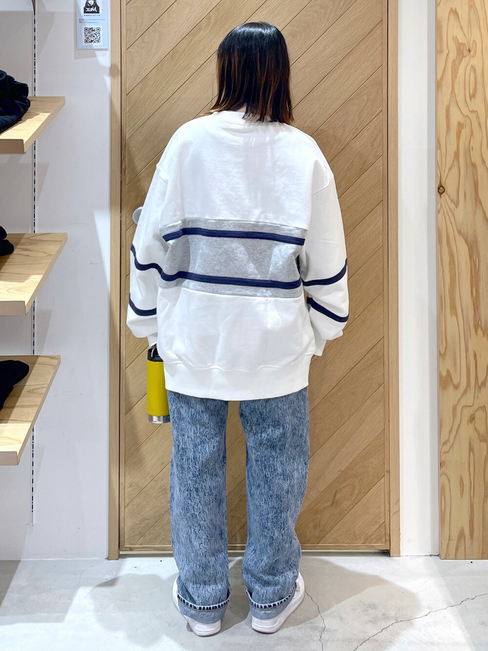 ブルー系のデニムパンツ、ホワイト系のスウェット、ホワイト系のスニーカーを着用したレディースの冬コーディネートの3枚目の写真