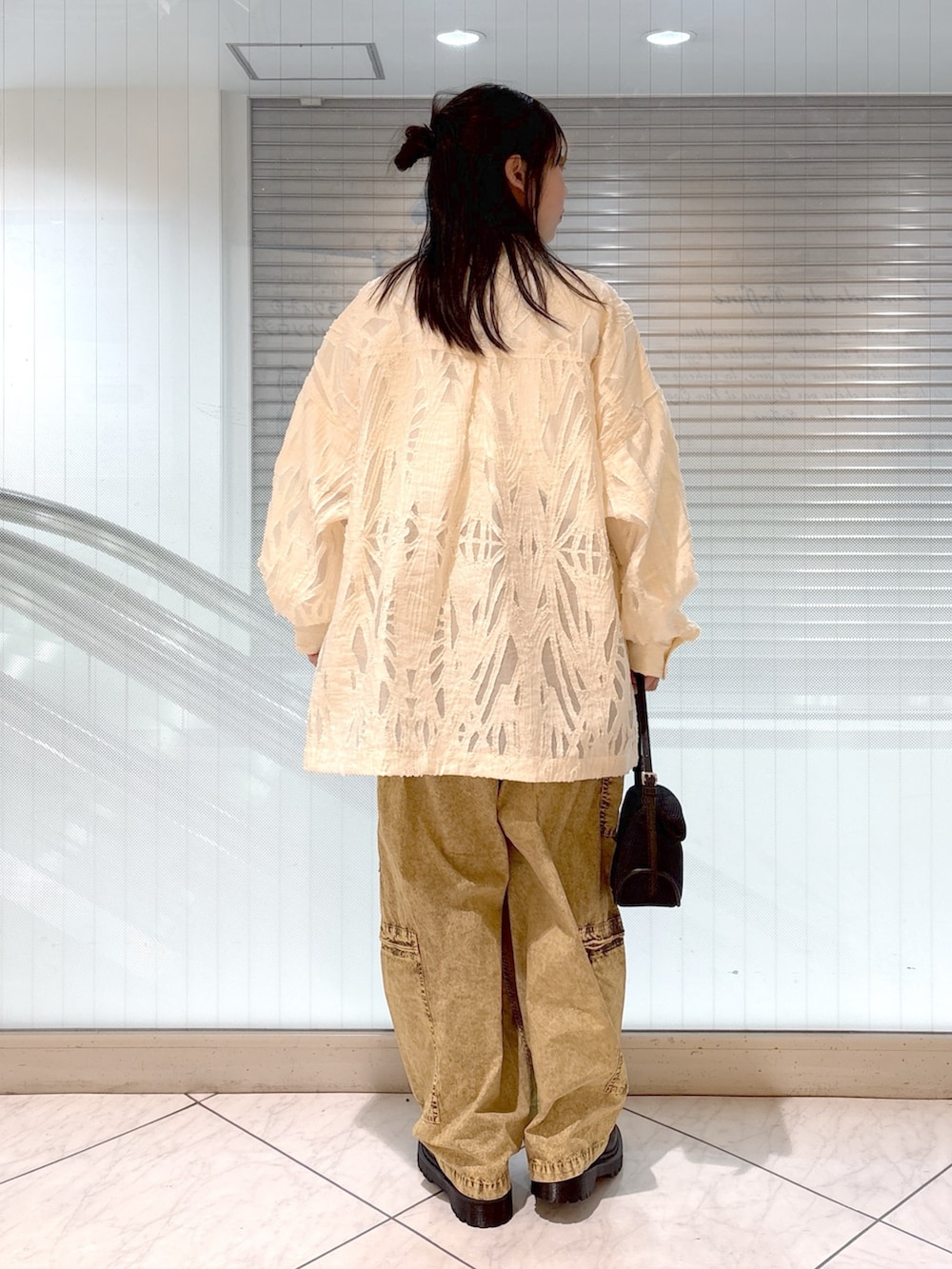 ブラック系のブーツ、ホワイト系のTシャツ/カットソー、ブラック系のショルダーバッグを着用したレディースの春コーディネートの3枚目の写真