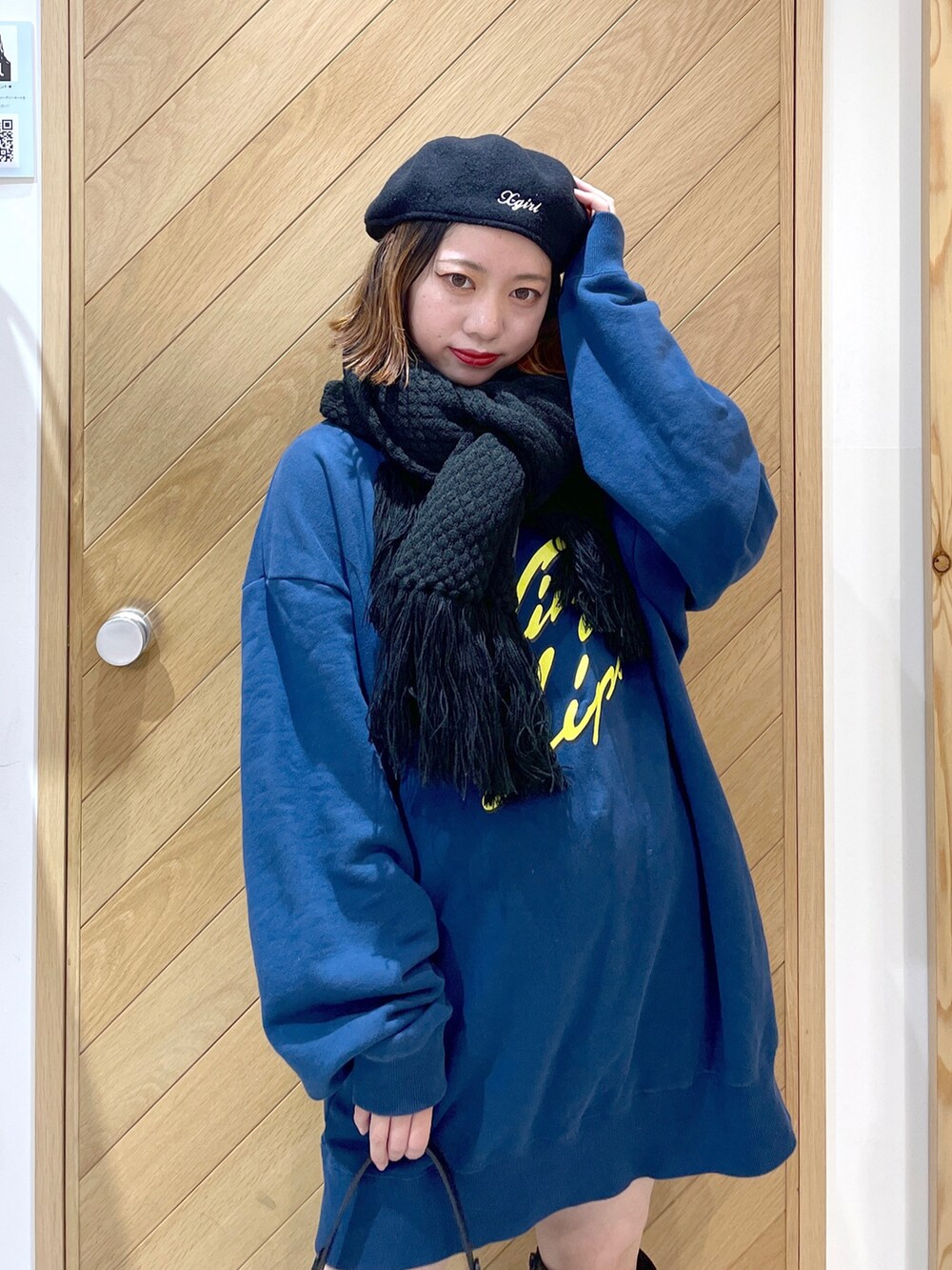 ブルー系のスウェット、ブラック系のブーツ、ブラック系のハンドバッグを着用したレディースの秋コーディネートの3枚目の写真