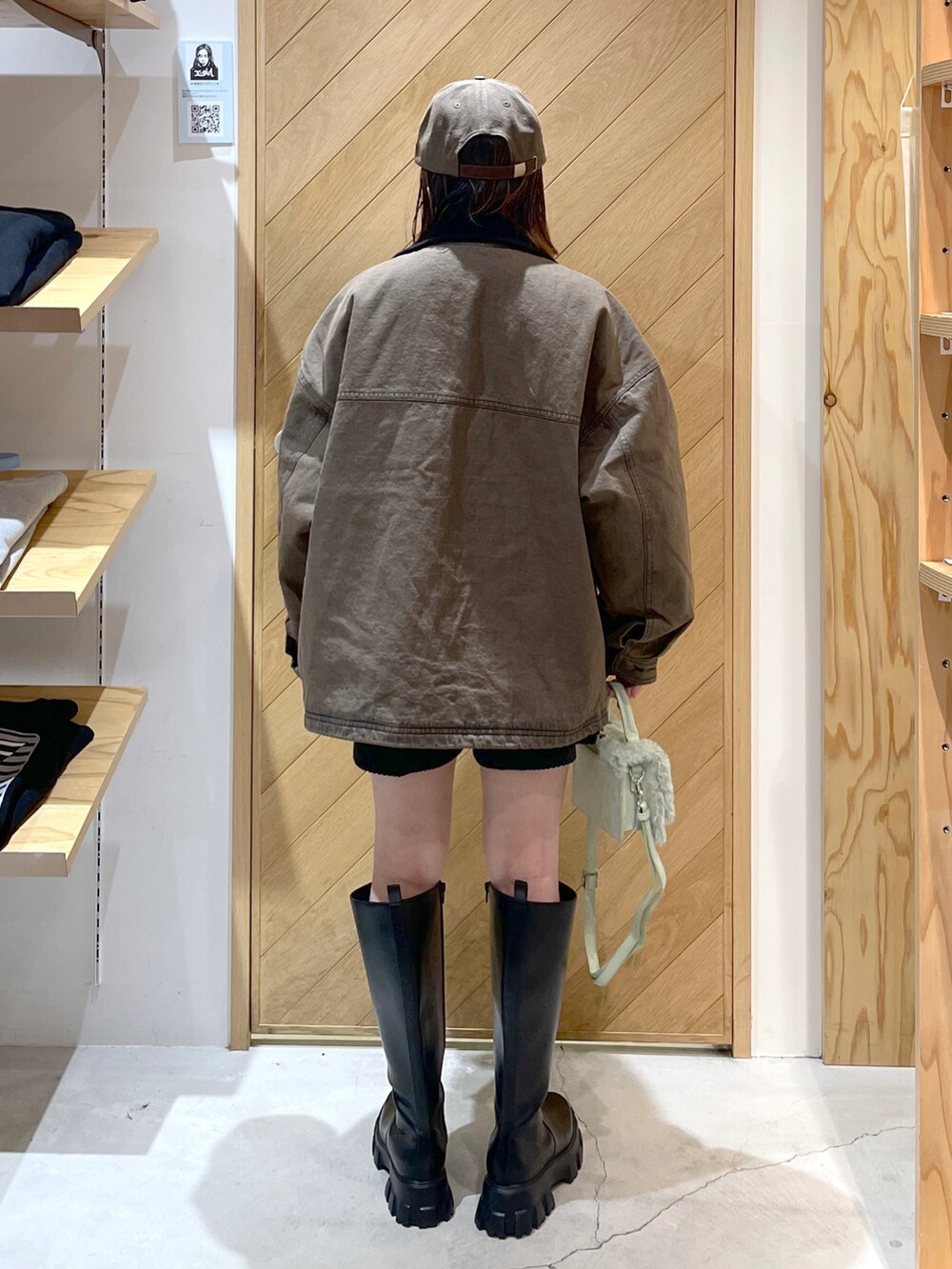 ブラック系のブーツ、グリーン系のショルダーバッグ、ブラウン系のデニムジャケットを着用したレディースの冬コーディネートの2枚目の写真