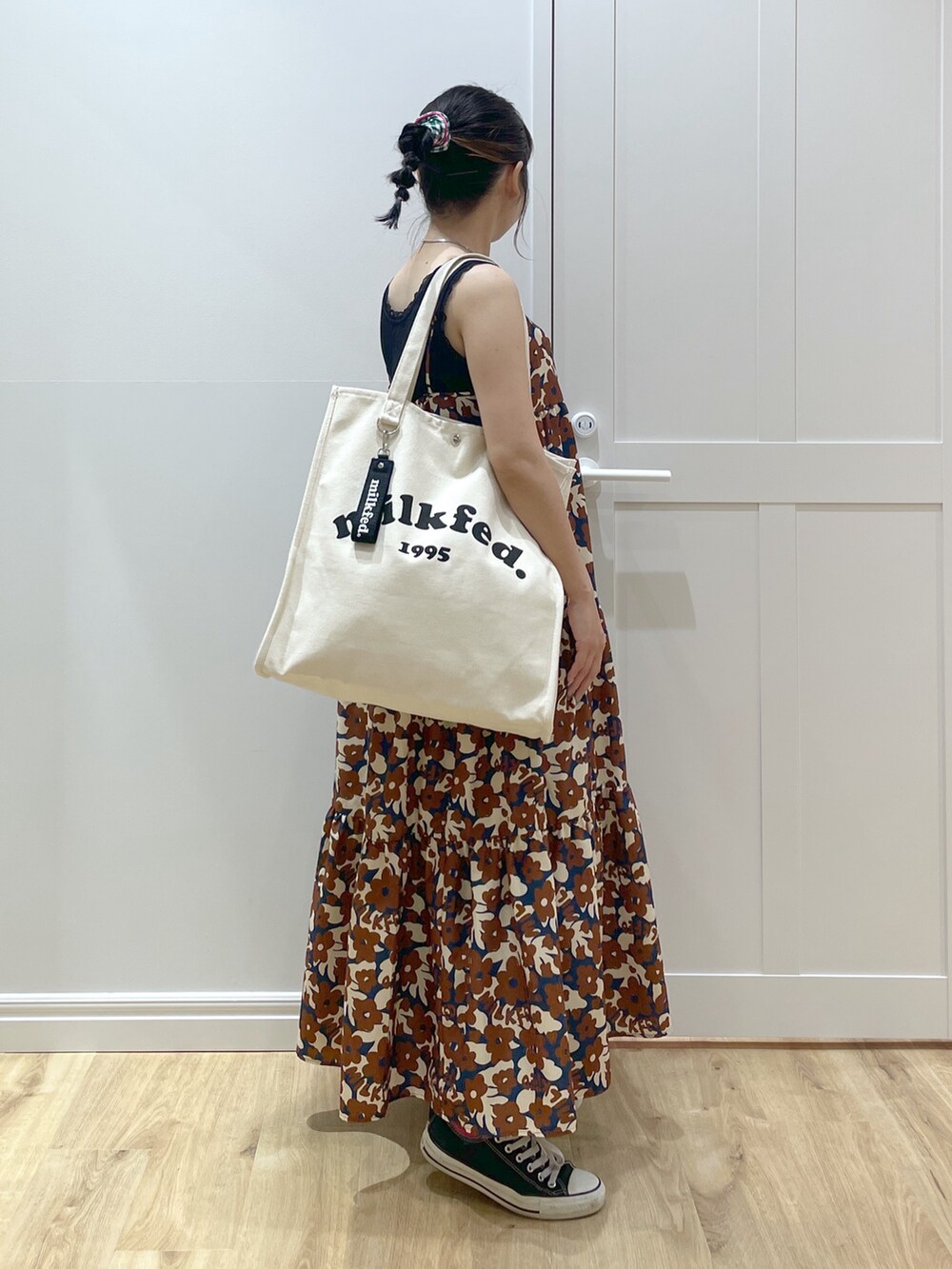 ブラウン系のワンピース、ブルー系のデニムパンツ、ブラック系のスニーカーを着用したレディースの春コーディネートの3枚目の写真