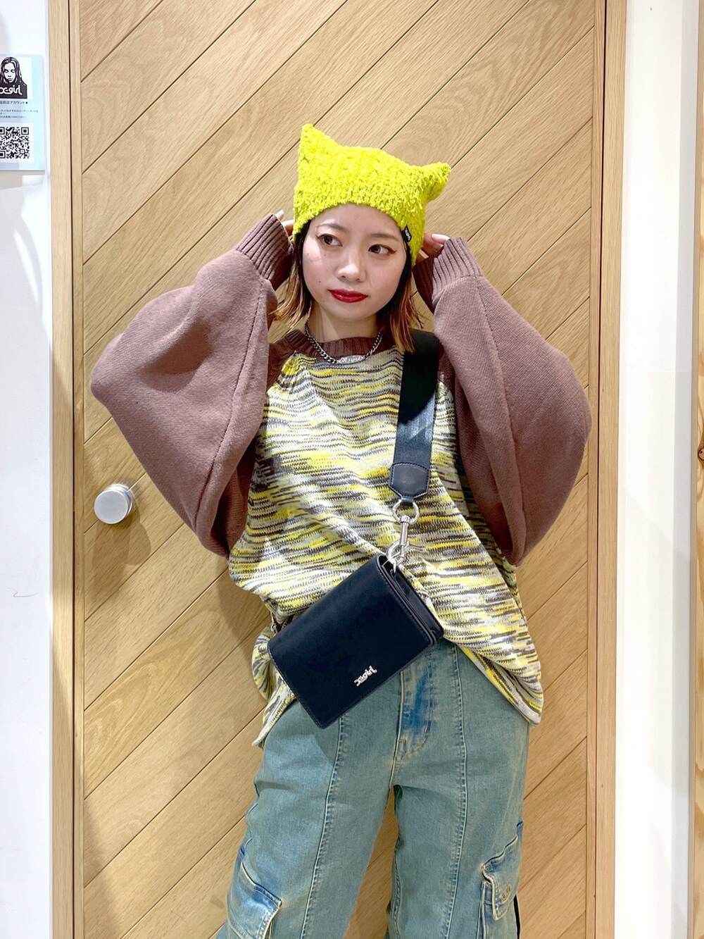 イエロー系のニット/セーター、ブルー系のカーゴパンツ、ホワイト系のスニーカーを着用したレディースの秋コーディネートの2枚目の写真