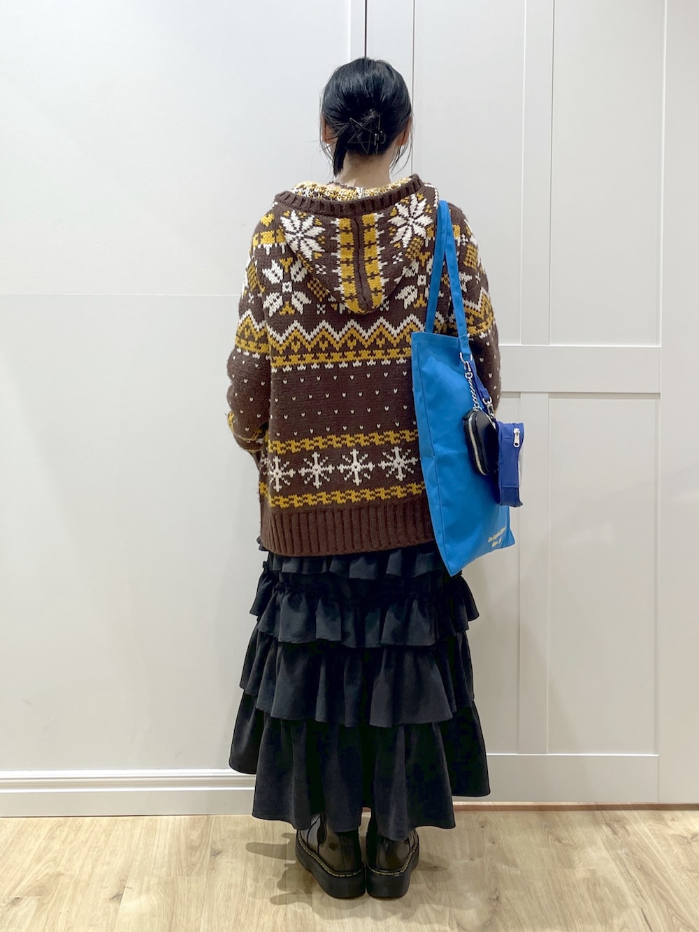 ブラウン系のその他アウター、ブラック系のスカート、ブラック系のブーツを着用したレディースの冬コーディネートの4枚目の写真