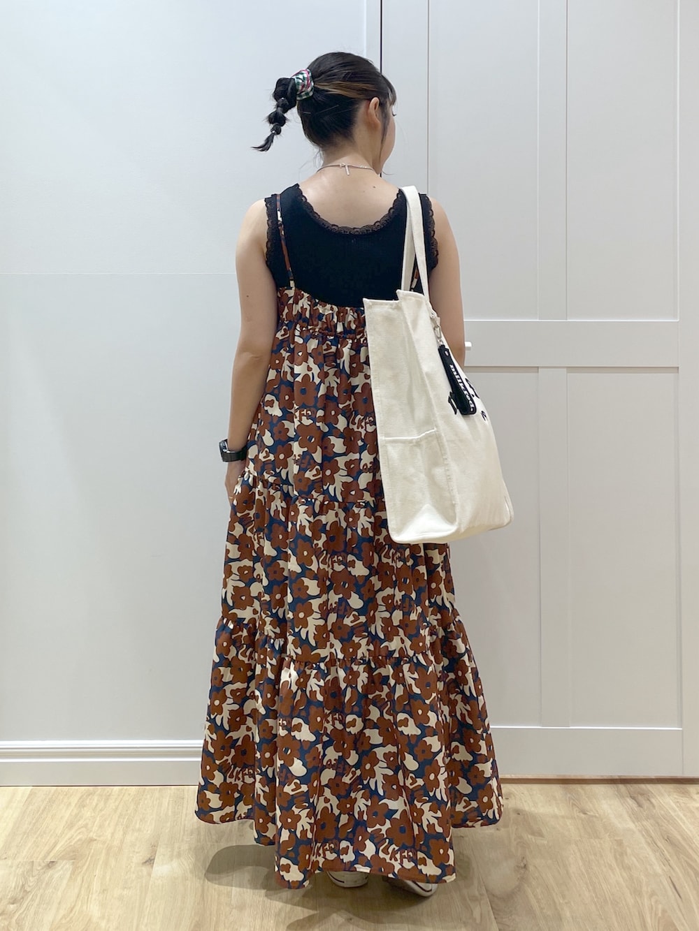 ブラウン系のワンピース、ブルー系のデニムパンツ、ブラック系のスニーカーを着用したレディースの春コーディネートの2枚目の写真
