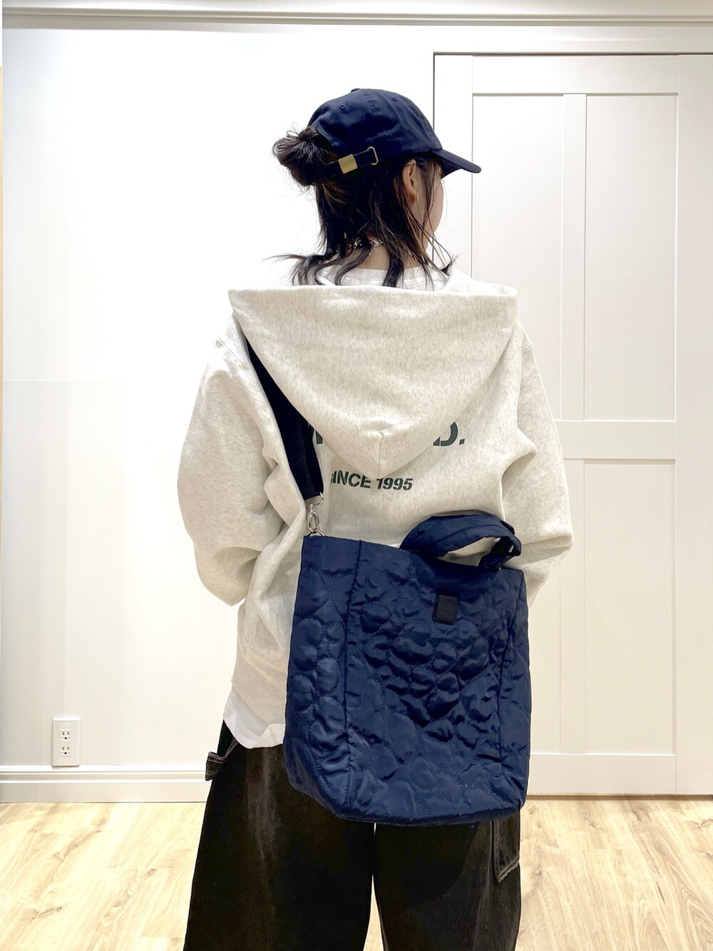 ブルー系のショルダーバッグ、ブラック系のデニムパンツ、ベージュ系のパーカーを着用したレディースの秋コーディネートの5枚目の写真