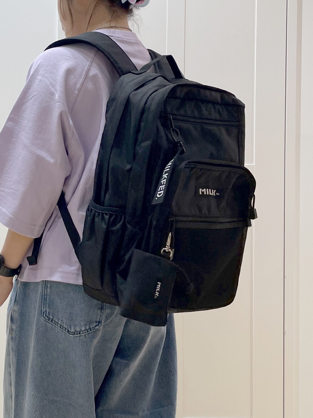 ブルー系のデニムパンツ、パープル系のTシャツ/カットソー、ブラック系のバックパック/リュックを着用したレディースの春コーディネートの3枚目の写真