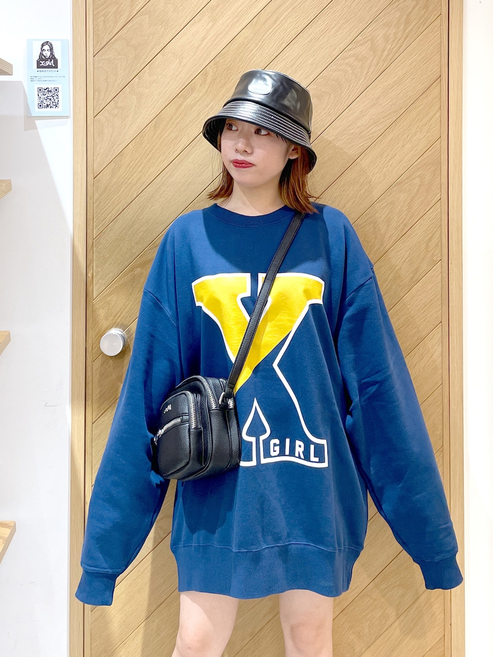 ブルー系のスウェット、ブラック系のショルダーバッグ、ブラック系のブーツを着用したレディースの秋コーディネートの2枚目の写真