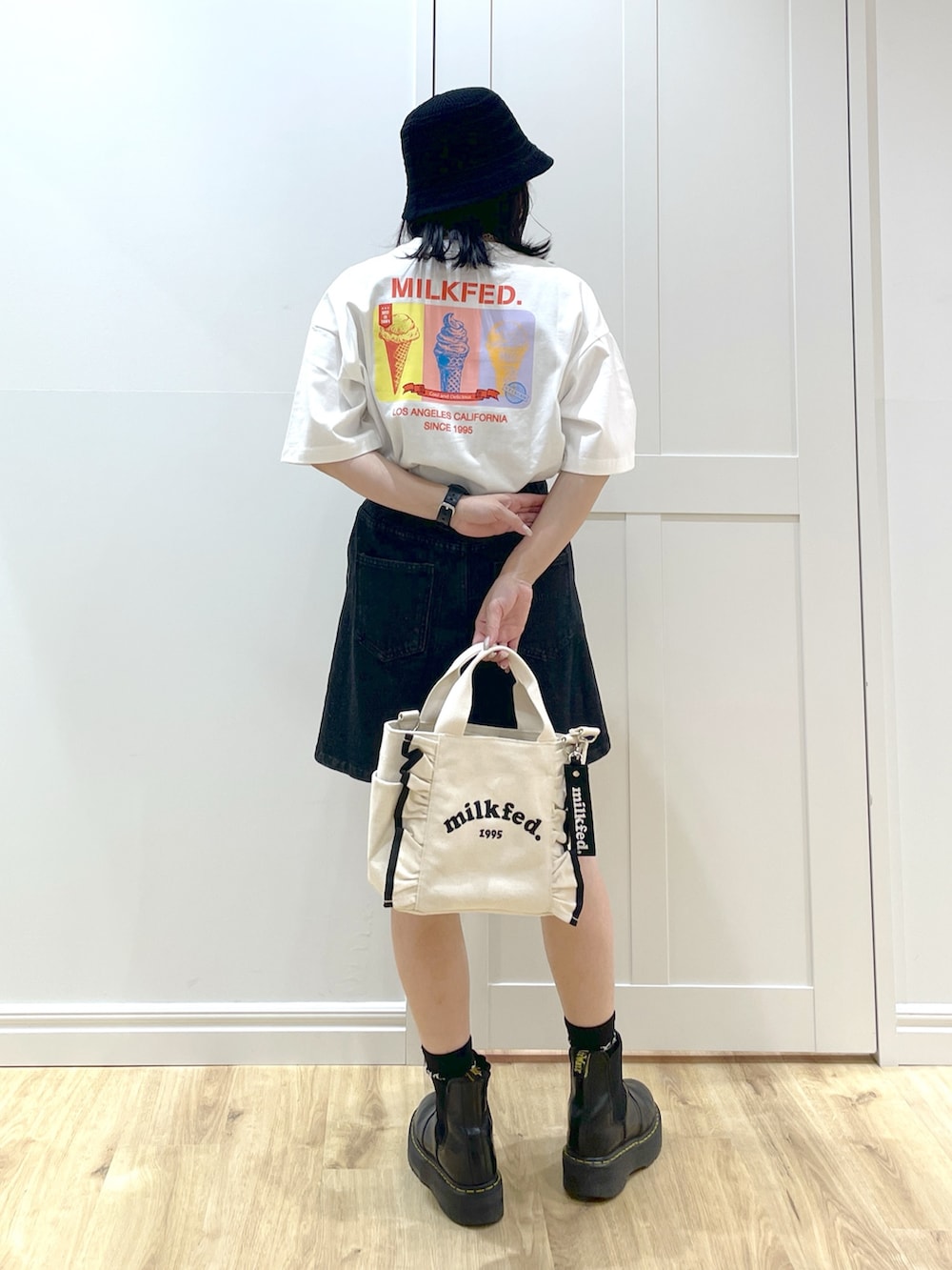 ホワイト系のショルダーバッグ、ブラック系のブーツ、ブラック系のデニムスカートを着用したレディースの夏コーディネートの2枚目の写真