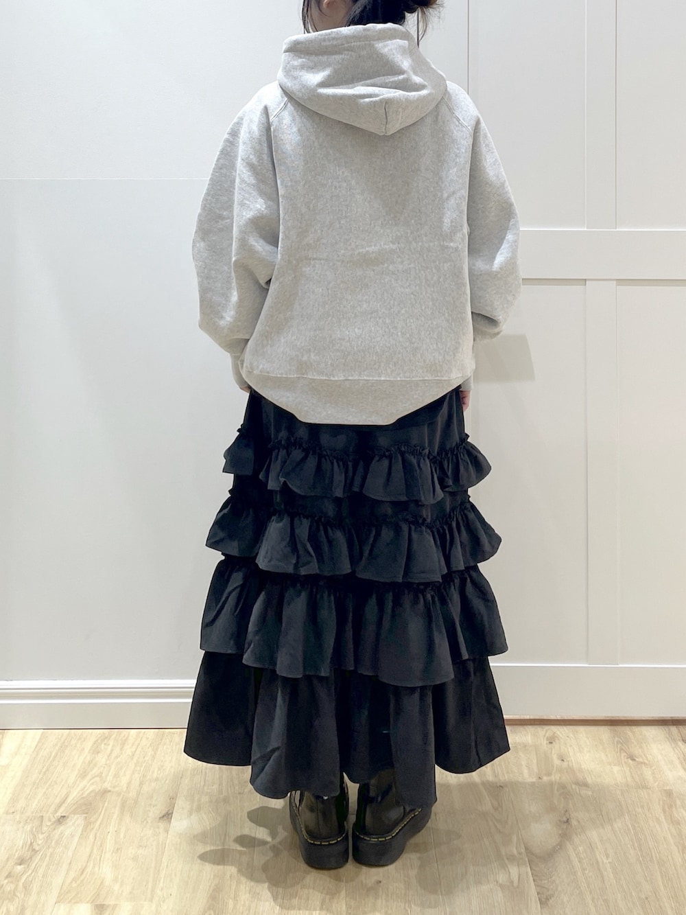 グレー系のパーカー、ブラック系のスカート、グリーン系のスタジャンを着用したレディースの冬コーディネートの6枚目の写真