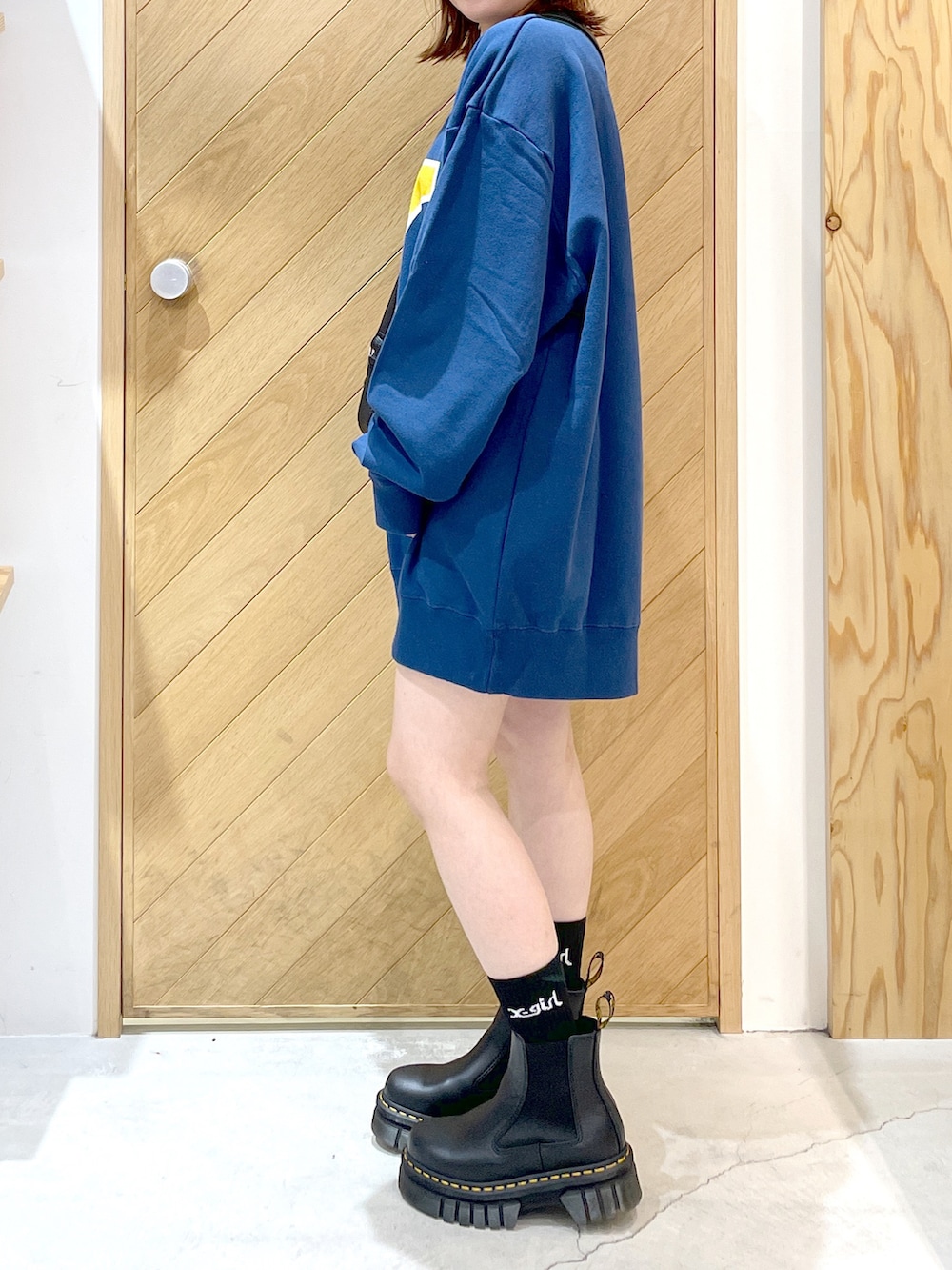 ブルー系のスウェット、ブラック系のショルダーバッグ、ブラック系のブーツを着用したレディースの秋コーディネートの3枚目の写真