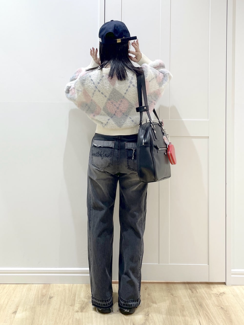 ブラック系のボストンバッグ、ブラック系のデニムパンツ、ホワイト系のニット/セーターを着用したレディースの秋コーディネートの4枚目の写真