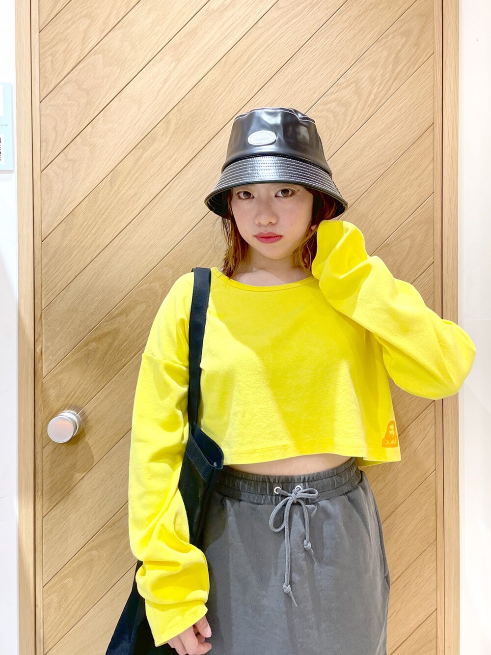 ブラック系のブーツ、イエロー系のTシャツ/カットソー、ブラック系のスカートを着用したレディースの秋コーディネートの2枚目の写真