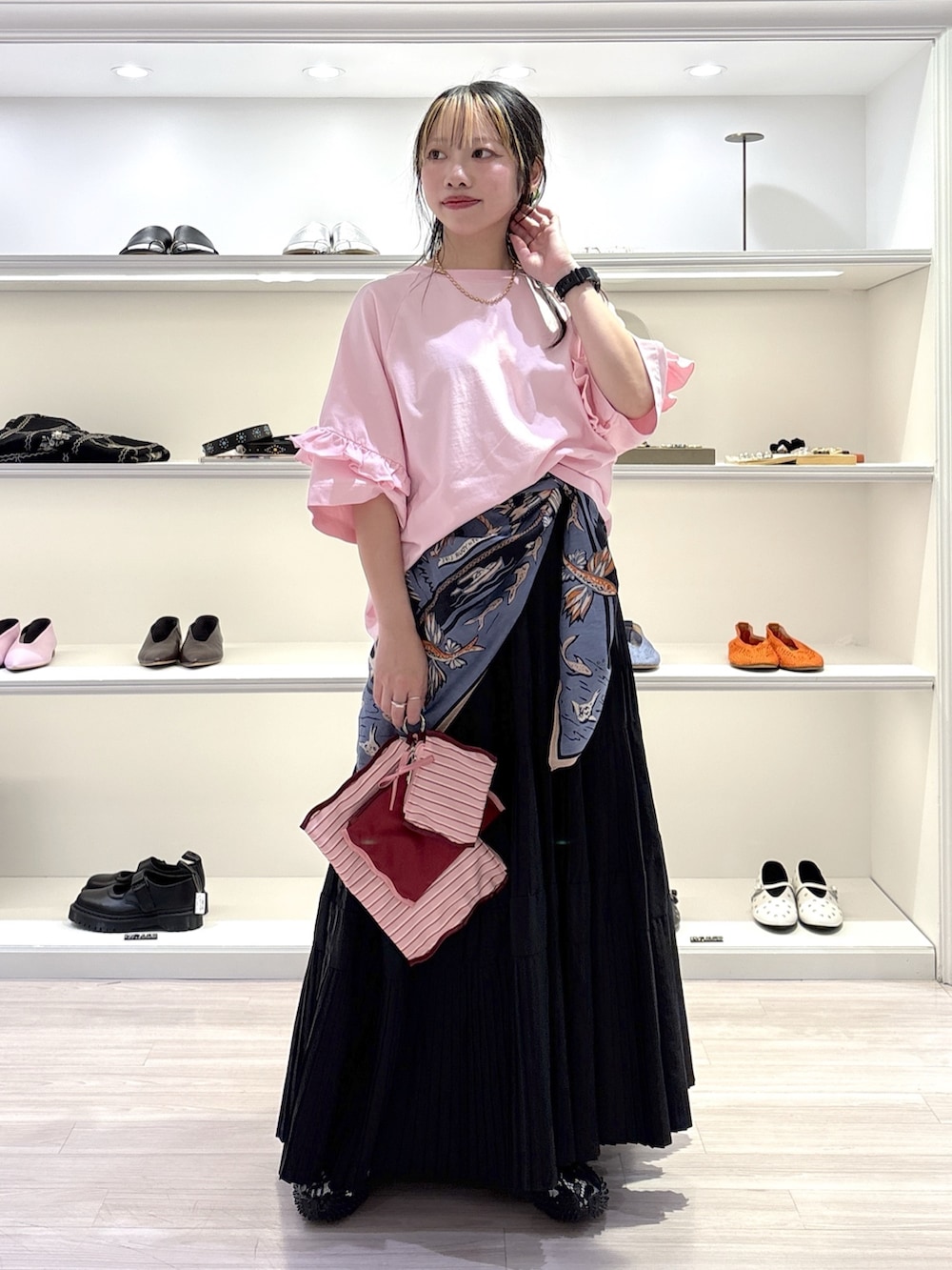 ピンク系のTシャツ/カットソー、ブラック系のスカート、ブラック系のスニーカーを着用したレディースの夏コーディネートの2枚目の写真