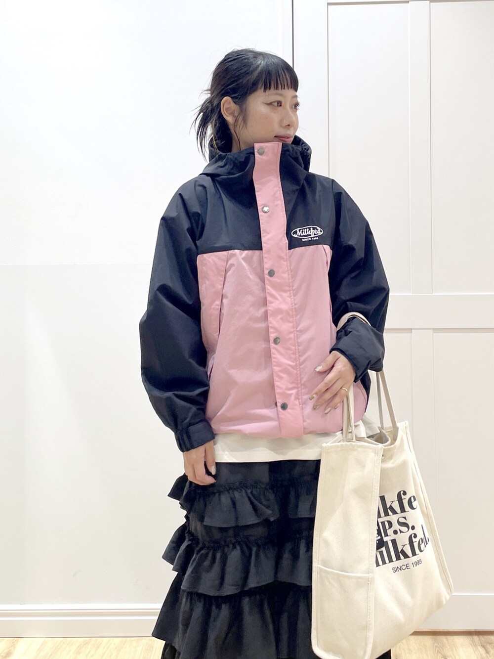 ブラック系のスカート、ホワイト系のTシャツ/カットソー、ピンク系のマウンテンパーカーを着用したレディースの秋コーディネートの5枚目の写真