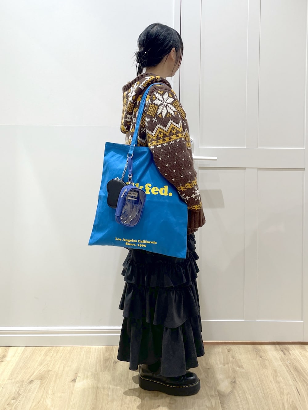 ブラウン系のその他アウター、ブラック系のスカート、ブラック系のブーツを着用したレディースの冬コーディネートの3枚目の写真