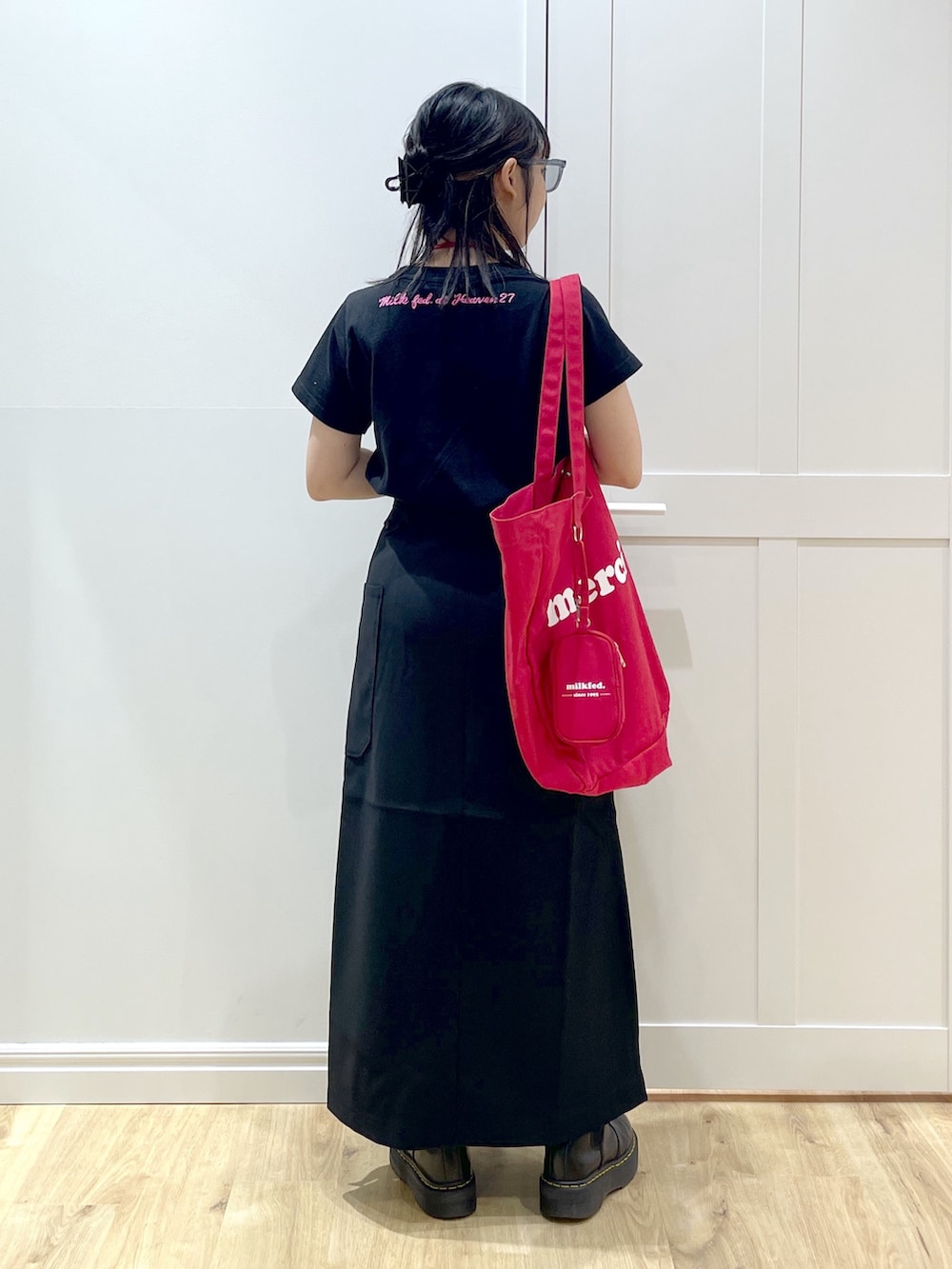 レッド系のトートバッグ、ブラック系のTシャツ/カットソー、ブラック系のスカートを着用したレディースの夏コーディネートの3枚目の写真