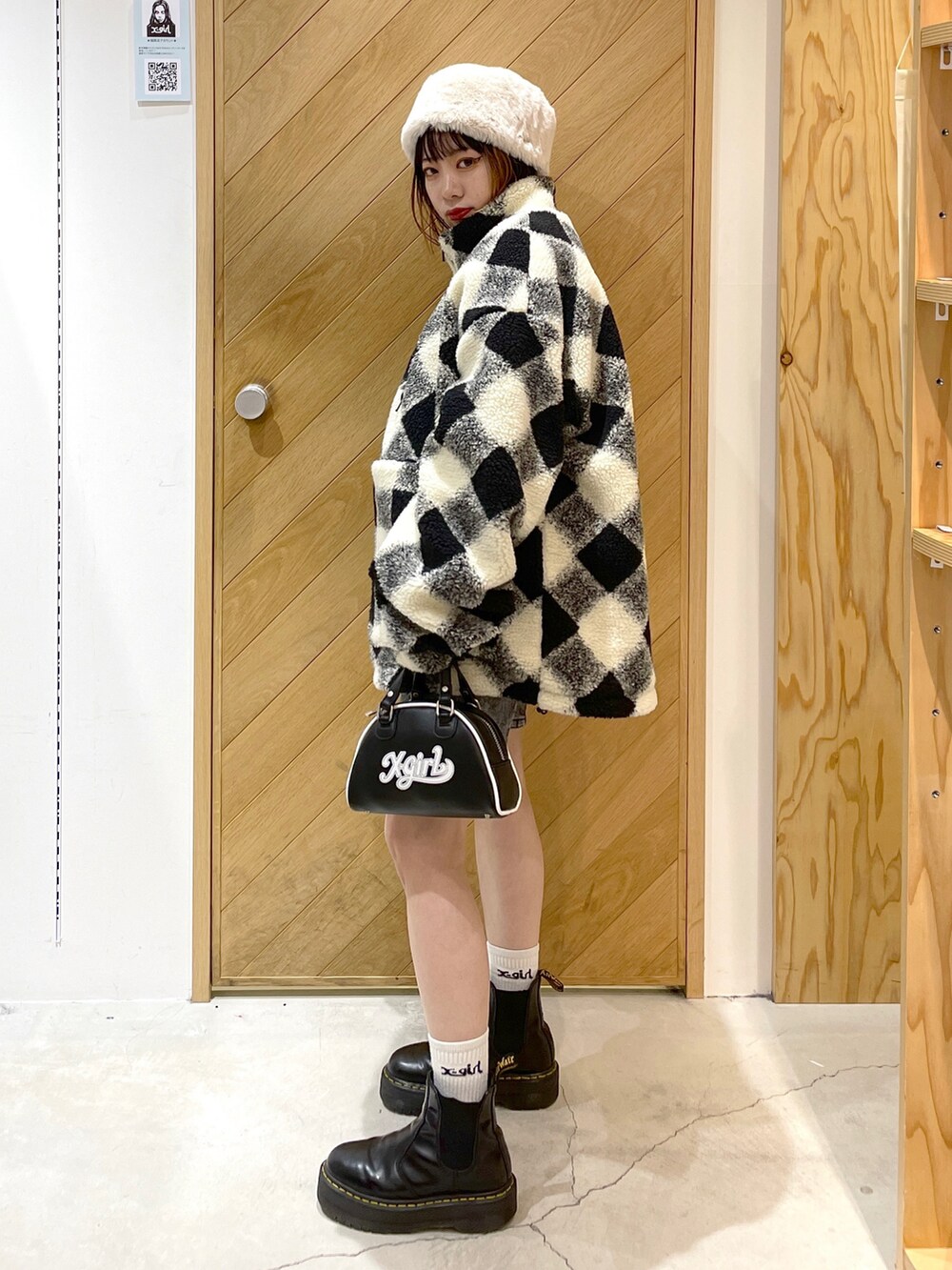 ホワイト系のブルゾン、ブラック系のブーツ、ブラウン系のデニムパンツを着用したレディースの冬コーディネートの2枚目の写真