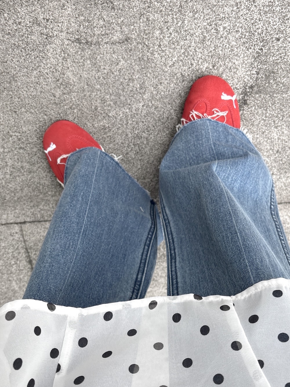 ブルー系のデニムパンツ、レッド系のスニーカー、ホワイト系のスカートを着用したレディースの春コーディネートの5枚目の写真