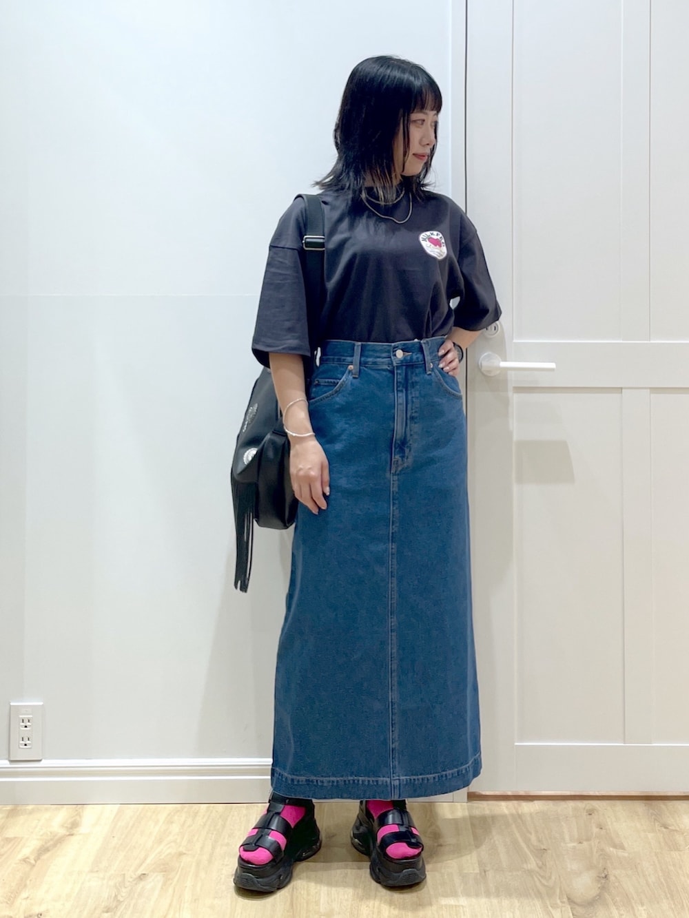 ブラック系のショルダーバッグ、グレー系のTシャツ/カットソー、ブルー系のデニムスカートを着用したレディースの夏コーディネートの2枚目の写真