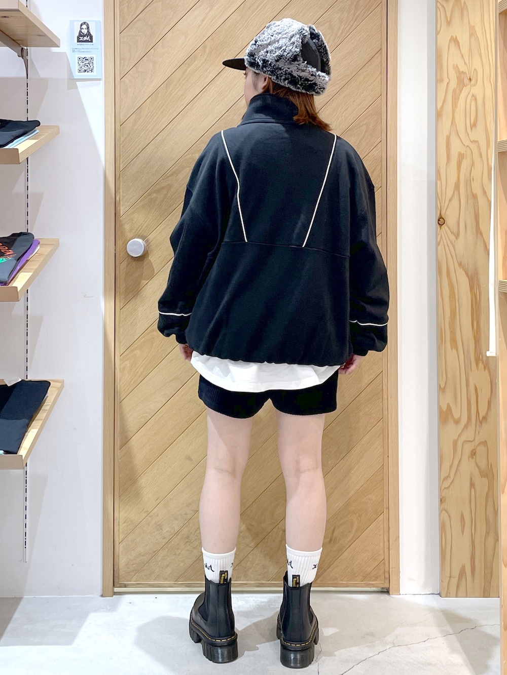 ブラック系のスウェット、ホワイト系のTシャツ/カットソー、ブラック系のブーツを着用したレディースの秋コーディネートの2枚目の写真