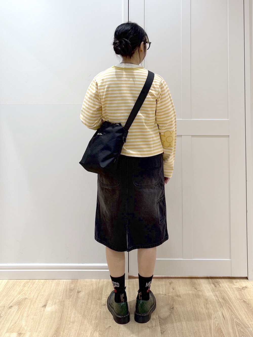 ブラック系のサロペット/オーバーオール、イエロー系のカーディガン/ボレロ、ホワイト系のTシャツ/カットソーを着用したレディースの春コーディネートの3枚目の写真