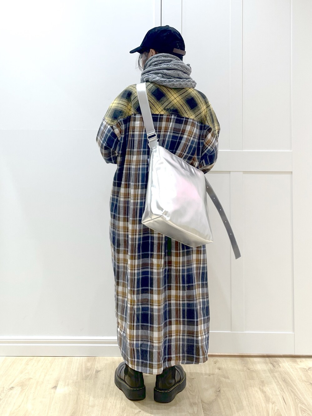 イエロー系のワンピース、ブラック系のブーツ、シルバー系のショルダーバッグを着用したレディースの秋コーディネートの2枚目の写真