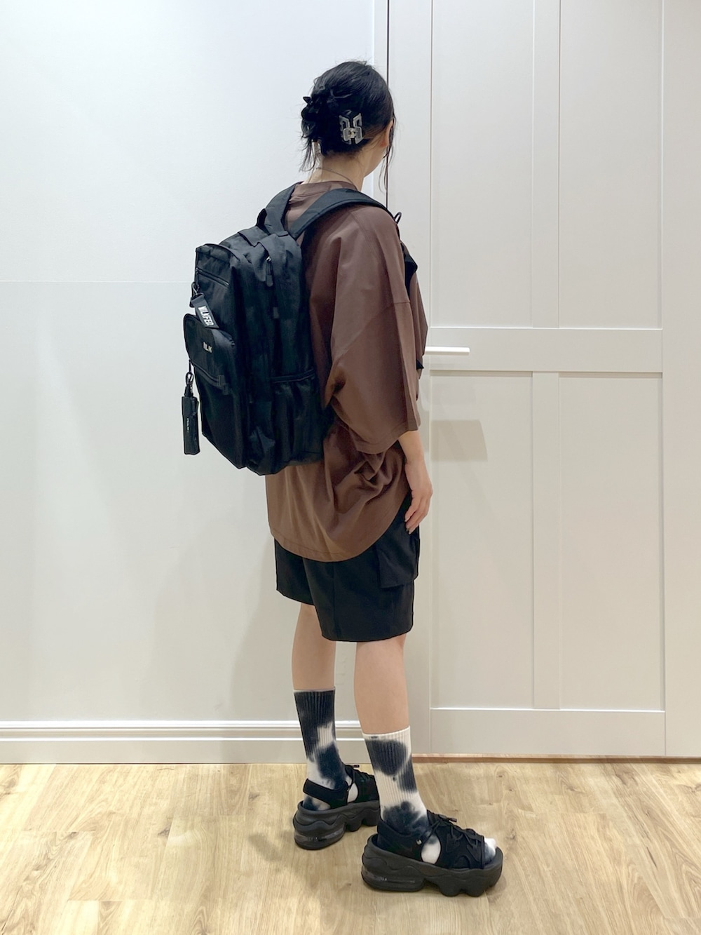 ブラック系のバックパック/リュック、ブラウン系のTシャツ/カットソー、ブラック系のサンダルを着用したレディースの春コーディネートの4枚目の写真