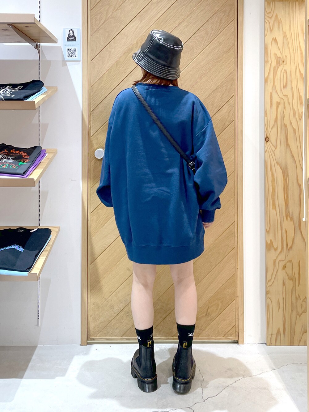 ブルー系のスウェット、ブラック系のショルダーバッグ、ブラック系のブーツを着用したレディースの秋コーディネートの4枚目の写真