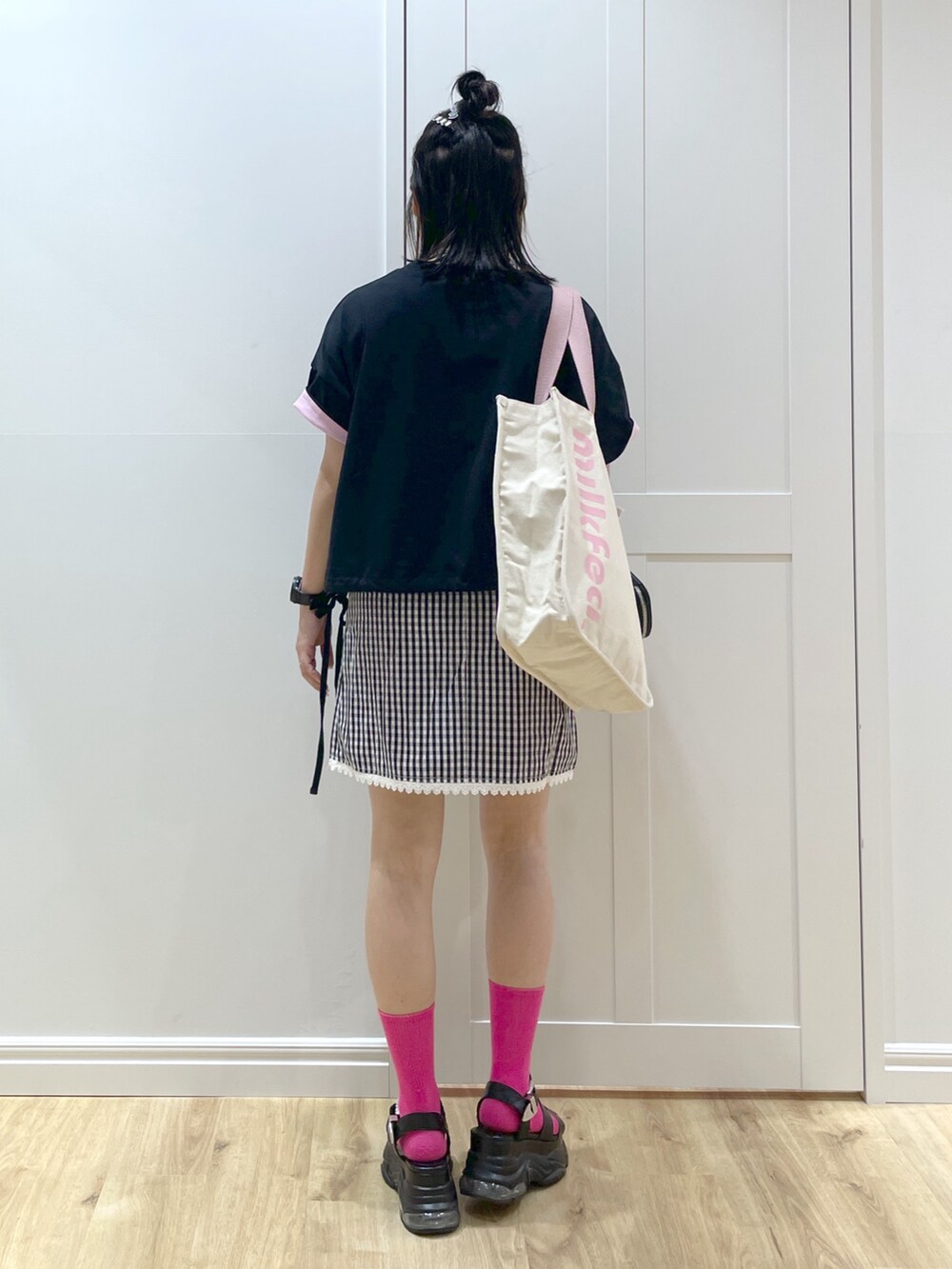 ホワイト系のトートバッグ、ブラック系のスカート、ブラック系のTシャツ/カットソーを着用したレディースの春コーディネートの2枚目の写真