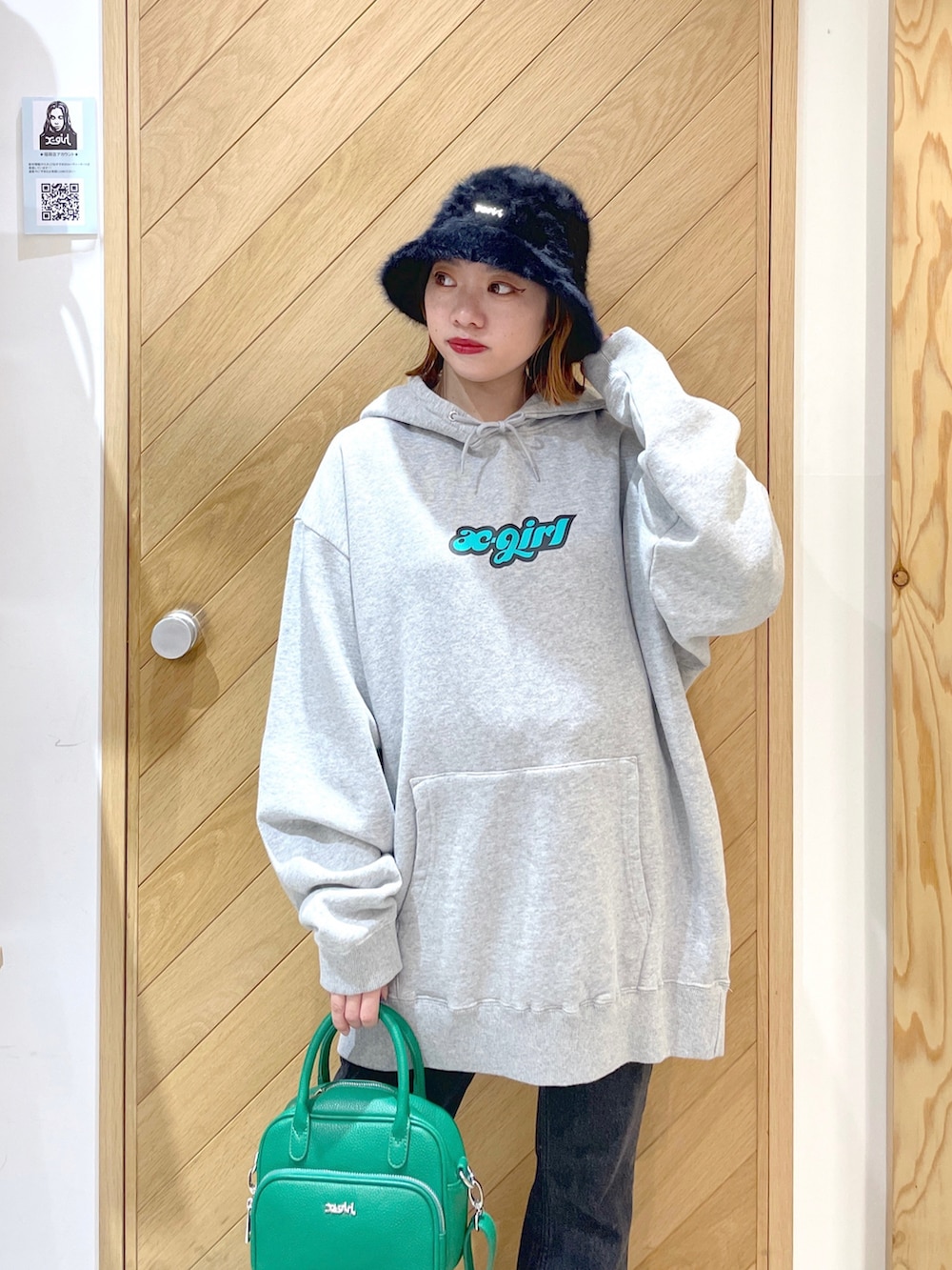 グリーン系のショルダーバッグ、グレー系のパーカー、ブラック系のブーツを着用したレディースの秋コーディネートの2枚目の写真